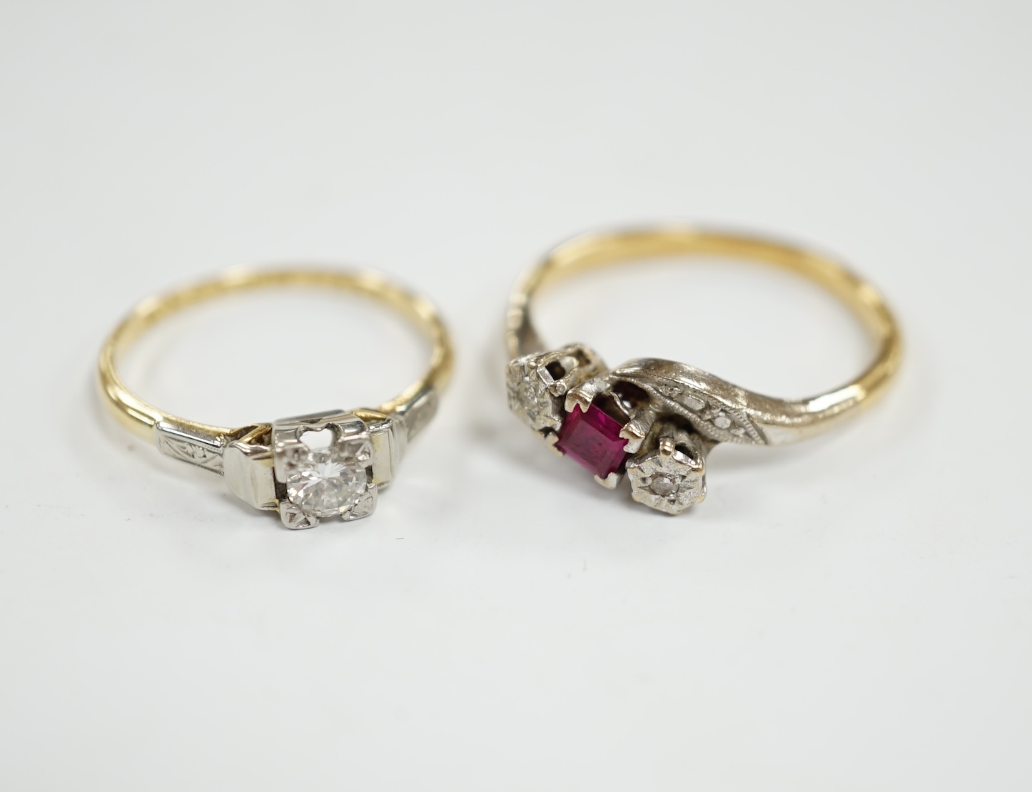 An 18ct, ruby and diamond chip set three stone crossover ring, size R and an 18ct, plat and solitaire diamond set ring, size N/O, gross weight 6.7 grams. Condition - fair